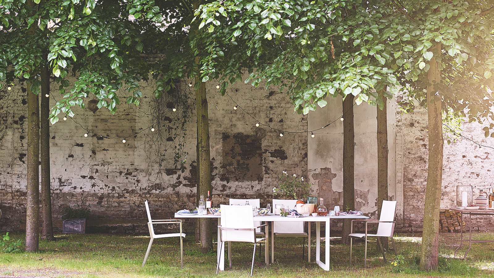 an outdoor table setting with string lights