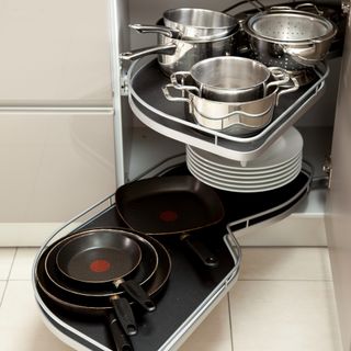 A kitchen cupboard with pots and pans