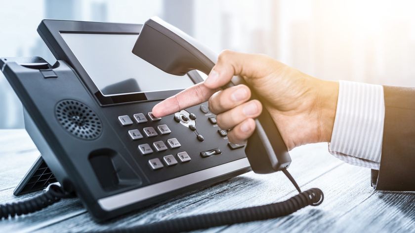 A hand reaching for a business phone.