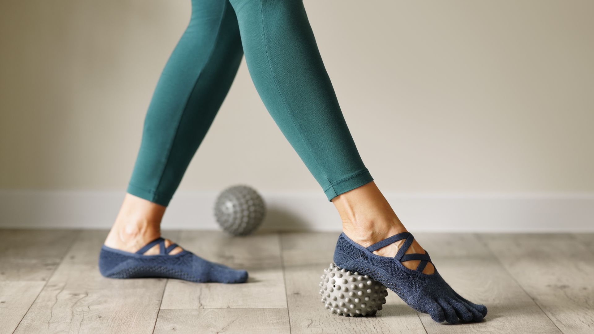 Woman massaging foot on spiked ball