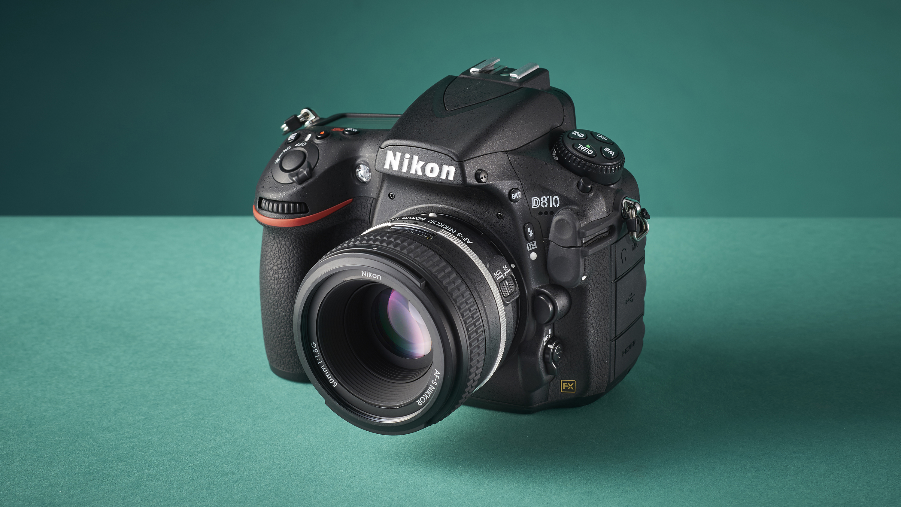 A Nikon D810 DSLR camera on a green studio-like background with light shining in from the left