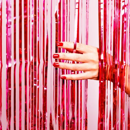 Hand with red nails moving through tinsel curtain