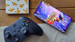Samsung Galaxy S22+ playing Apex Legends: Mobile beside an Xbox controller and coaster