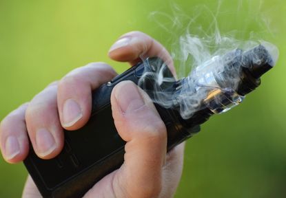 A person's hand holding an e-cigarette.