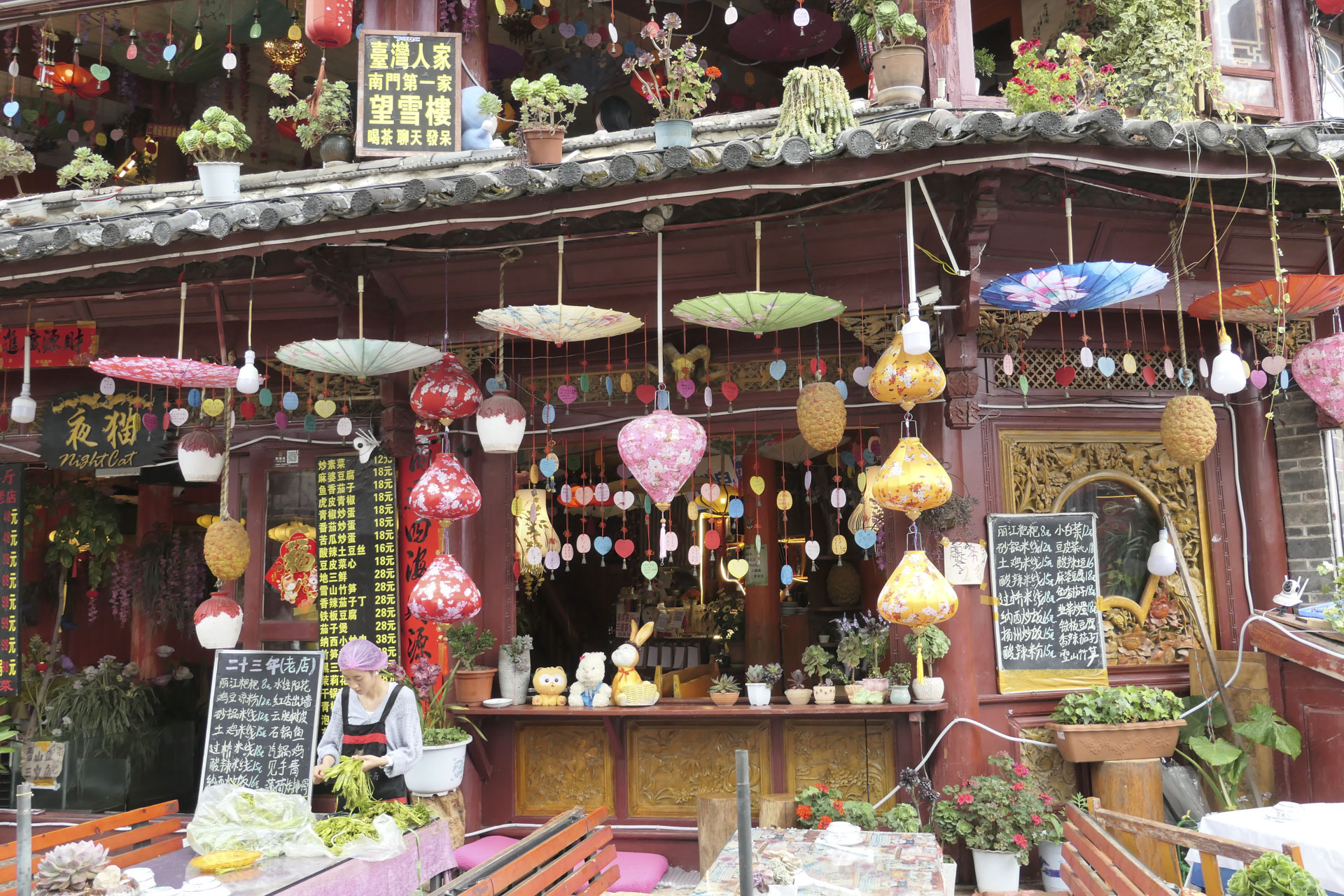 The outside of a Chinese restaurant which is decked with colorful decorations and umbrellas