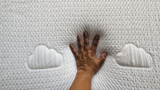 Hand resting on surface of Puffy Lux Hybrid mattress