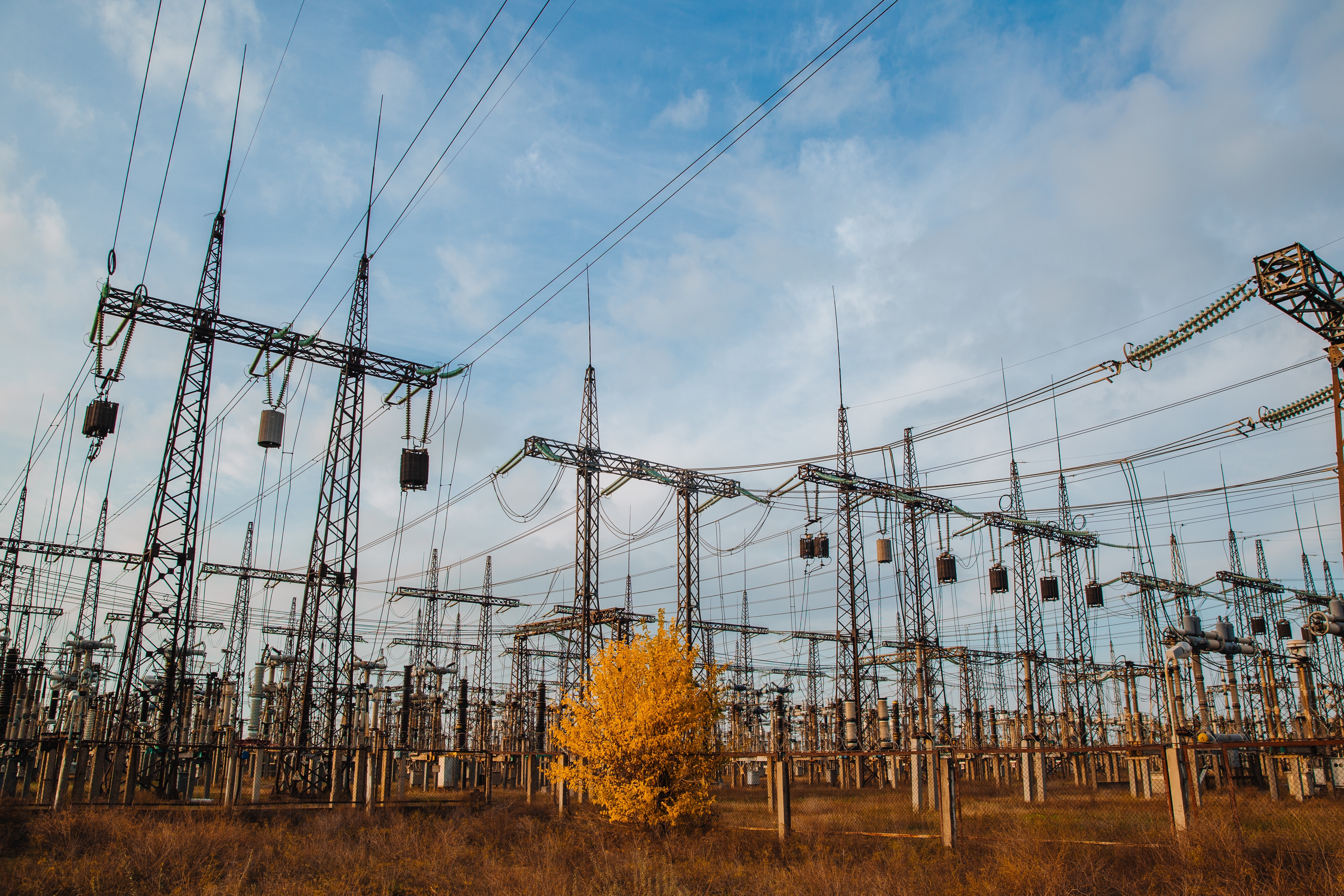 Electrical pylons and high voltage power lines are behind a barbed wire fence. critical infrastructure