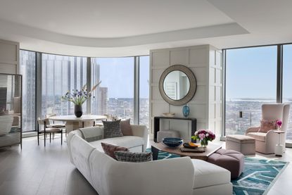 living room with white sectional sofa with round dining table and full height windows with views of city skyline