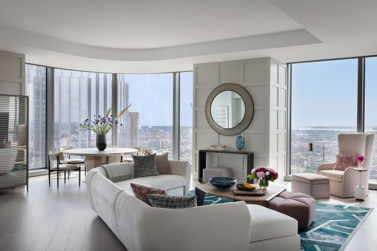 living room with white sectional sofa with round dining table and full height windows with views of city skyline