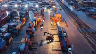 A vast lot of storage containers seen from above, with a couple of trucks in frame.