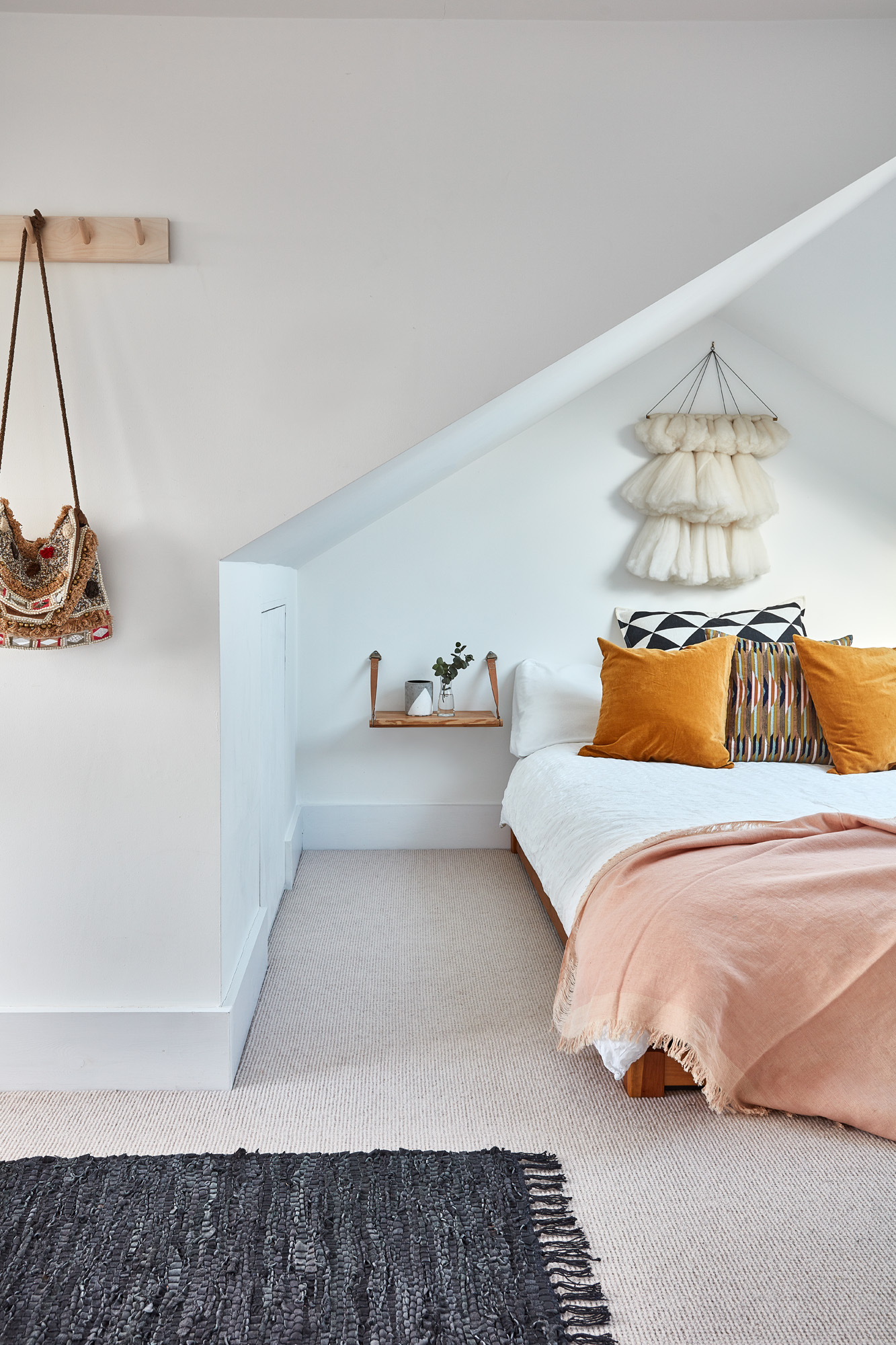 Lily Pickard house: loft bedroom with white walls, pink throw