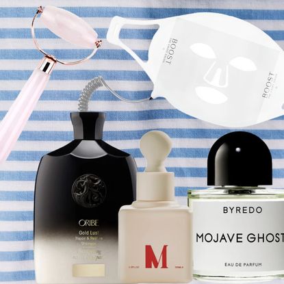 a pink jade roller, oribe shampoo, byredo perfume, dr. diamond serum, and omniluxe face mask on a blue and white stripe towel background