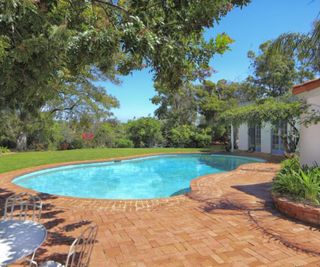 Marilyn Monroe’s house - A large curvy pool with red brick surround, shaded by trees