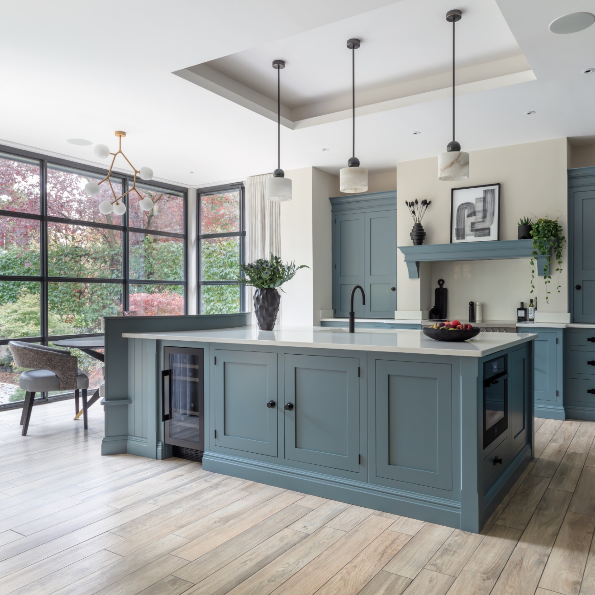 blue kitchen with large kitchen island, wine cooler, banquette seating, crittall doors to outside