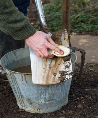 Brushing mud and soil off a spade