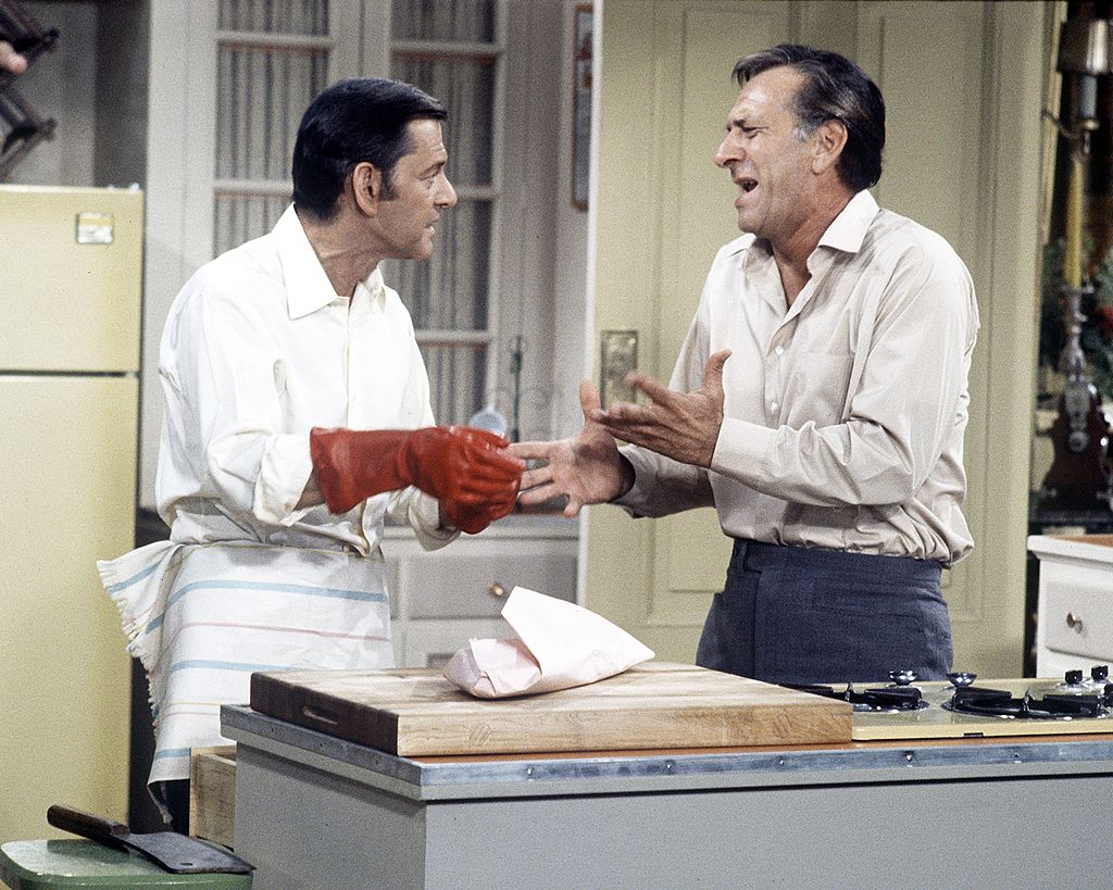 Felix and Oscar of the 1970s TV show, The Odd Couple, having a disagreement in their shared kitchen.