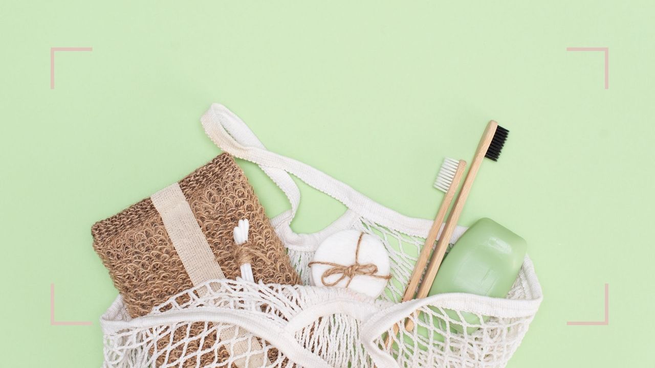 A netted bag filled with sustainable beauty items including a toothbrush, soap, loofah