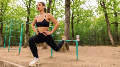 woman in park uses low bar to do Bulgarian split squat