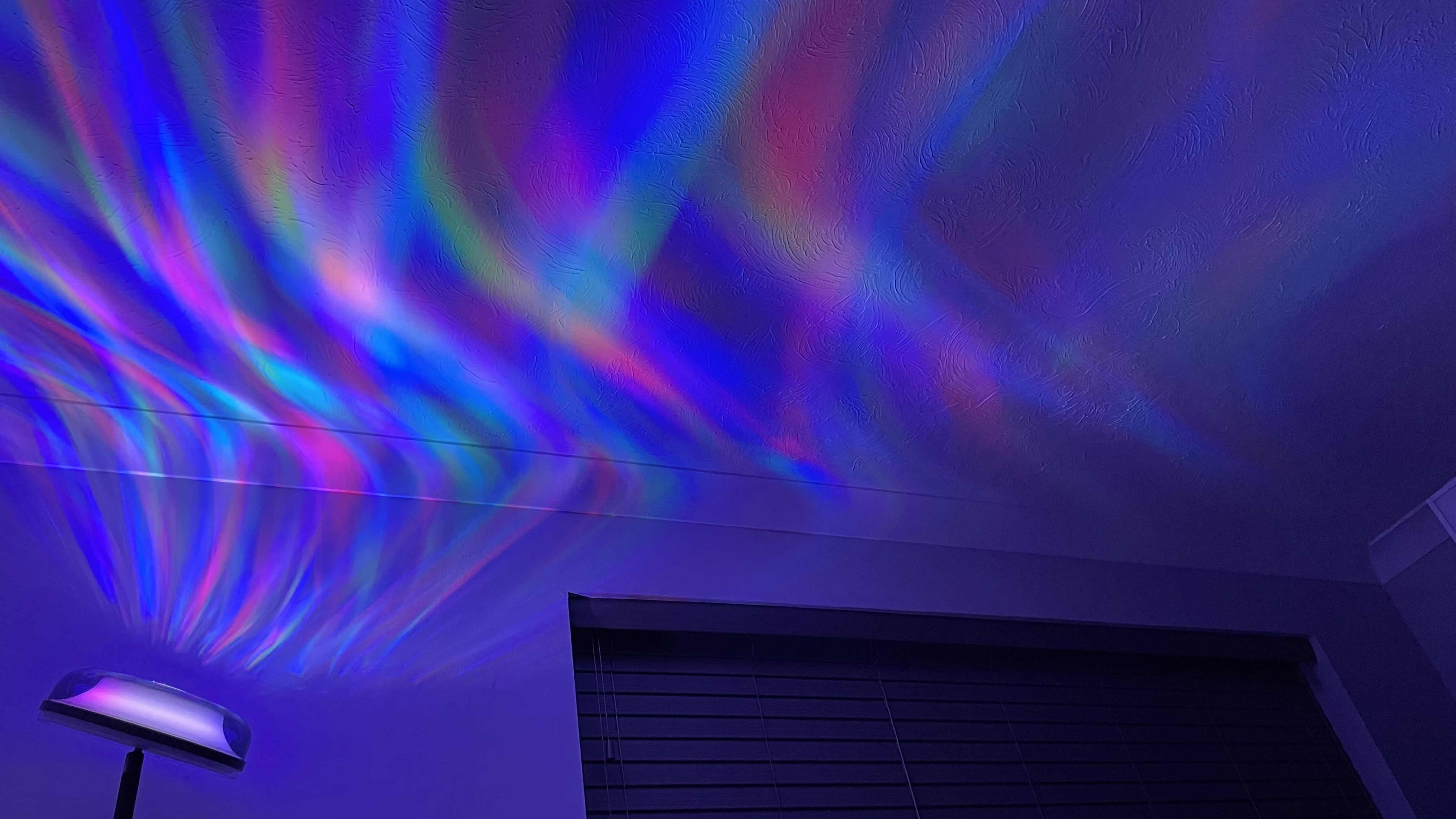 The Govee Uplighter Floor Lamp is projecting an aurora borealis effect onto a bedroom ceiling.