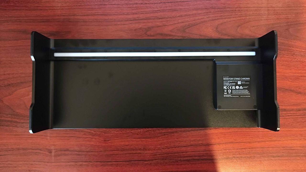 Razer Monitor Stand Chroma lying on woodgrain desk with bottom facing upwards.