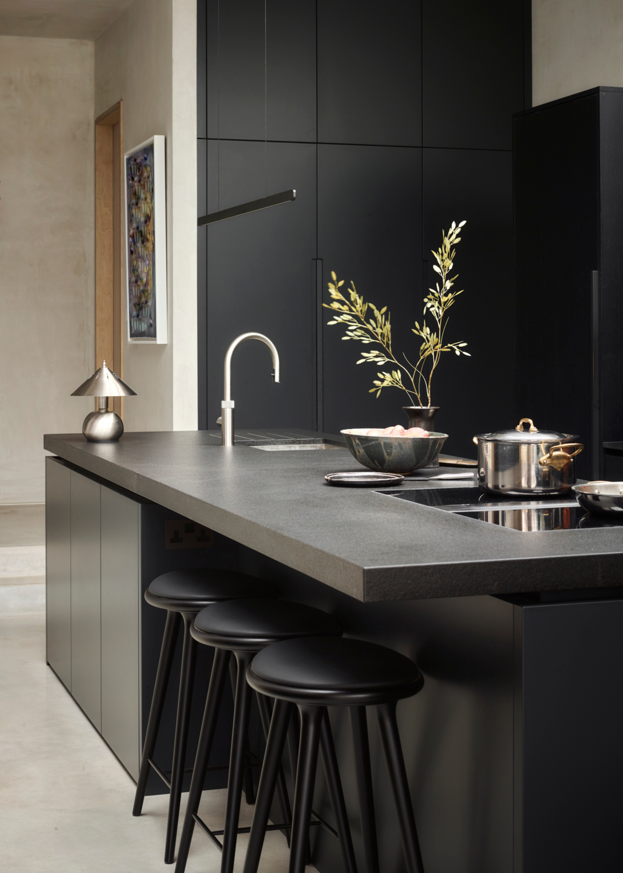 a sleek all black kitchen with silver accessories on top of a kitchen island