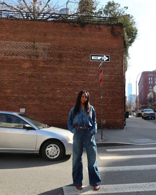 Sierra wears a denim button-down, brown belt, denim pants, and brown shoes.