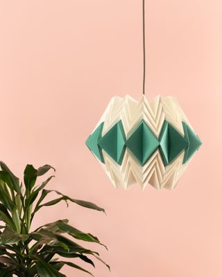 Green and cream origami lampshade against a pink backdrop