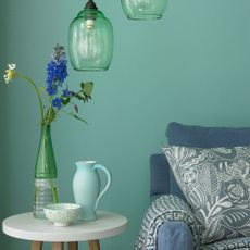 blue wall with armchair cushion and plant in vase