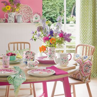 dining table with chairs cushions teacup fruit bowl and flower vase