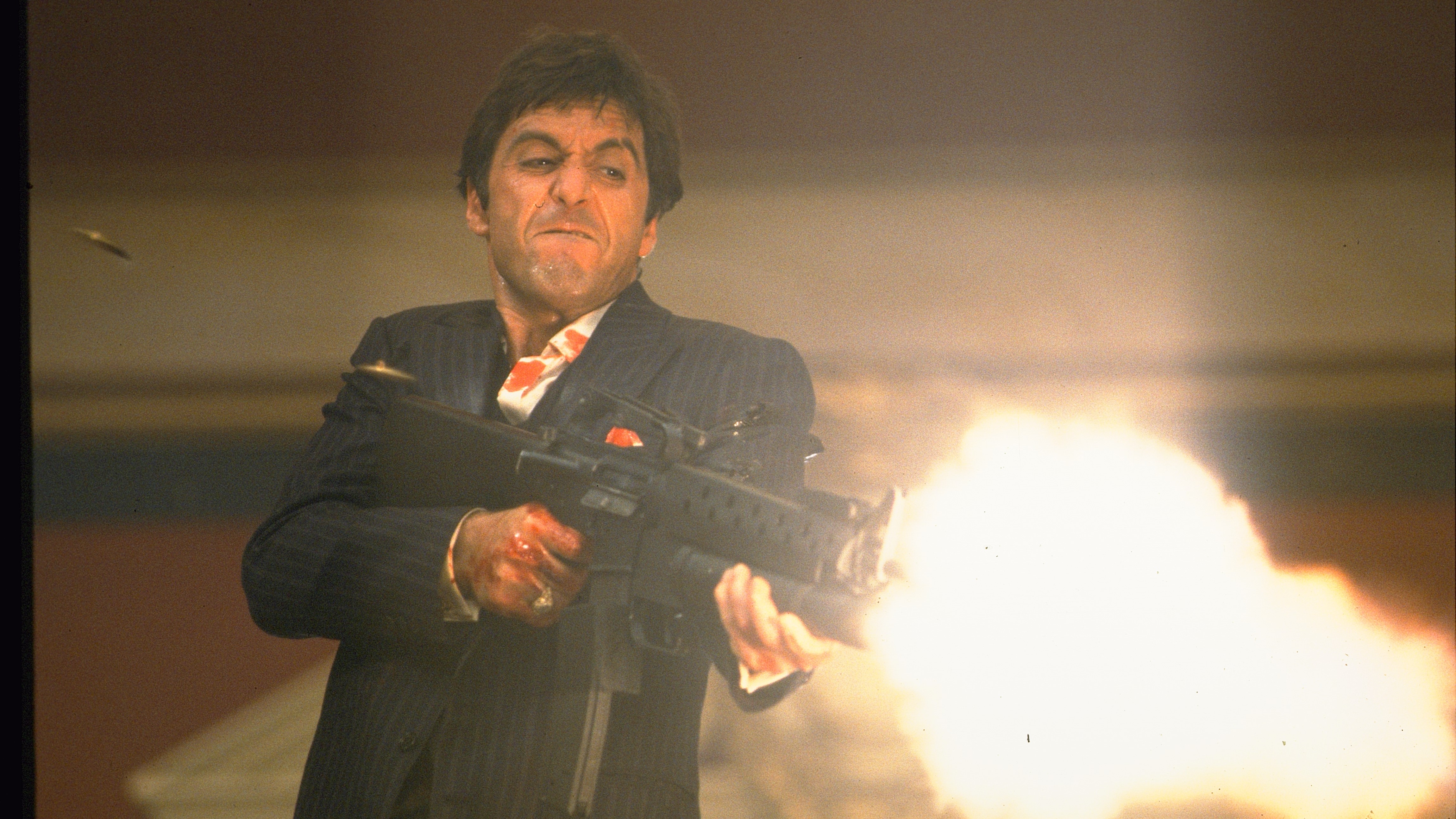 Al Pacino als Tony Montana mit Narbengesicht, der ein Sturmgewehr abfeuert