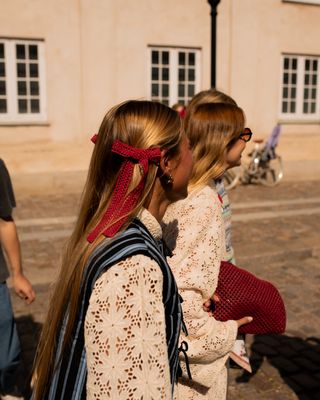 two blonde women at Copenhagen Fashion Week wearing red hair bows while walking between shows