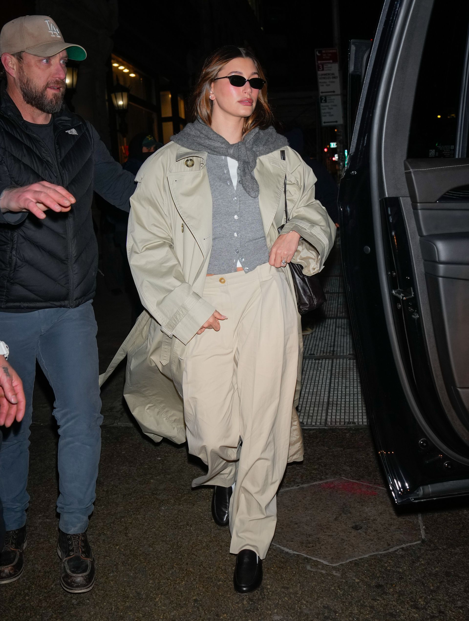 Hailey Bieber wearing a gray cardigan with another gray sweater tied around her shoulders.