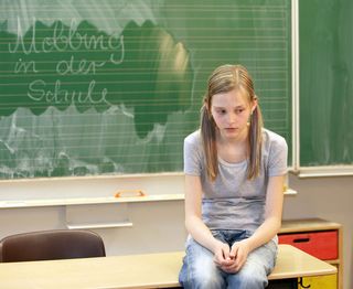 sad girl sits on school desk