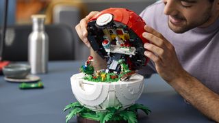 A man lifts the lid of a Lego Poke Ball with a diorama inside