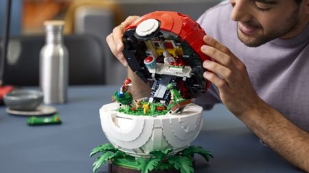 A man lifts the lid of a Lego Poke Ball with a diorama inside