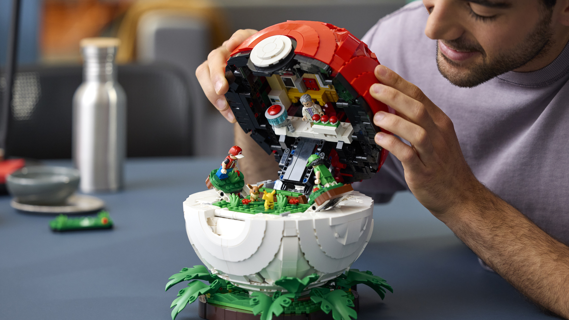 A man lifts the lid of a Lego Poke Ball with a diorama inside