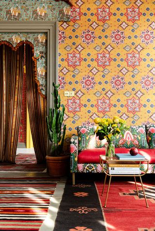 Patterned and maximalist hallway, with patterned yellow wallpaper, colourful patterned carpet and colourful sofa