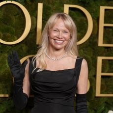 Pamela Anderson on the 2025 golden globes carpet in a black gown and opera gloves