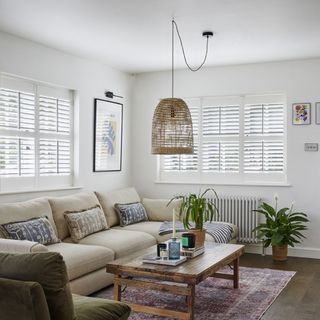 living room with shutters, cream sofa and coffee table on rug