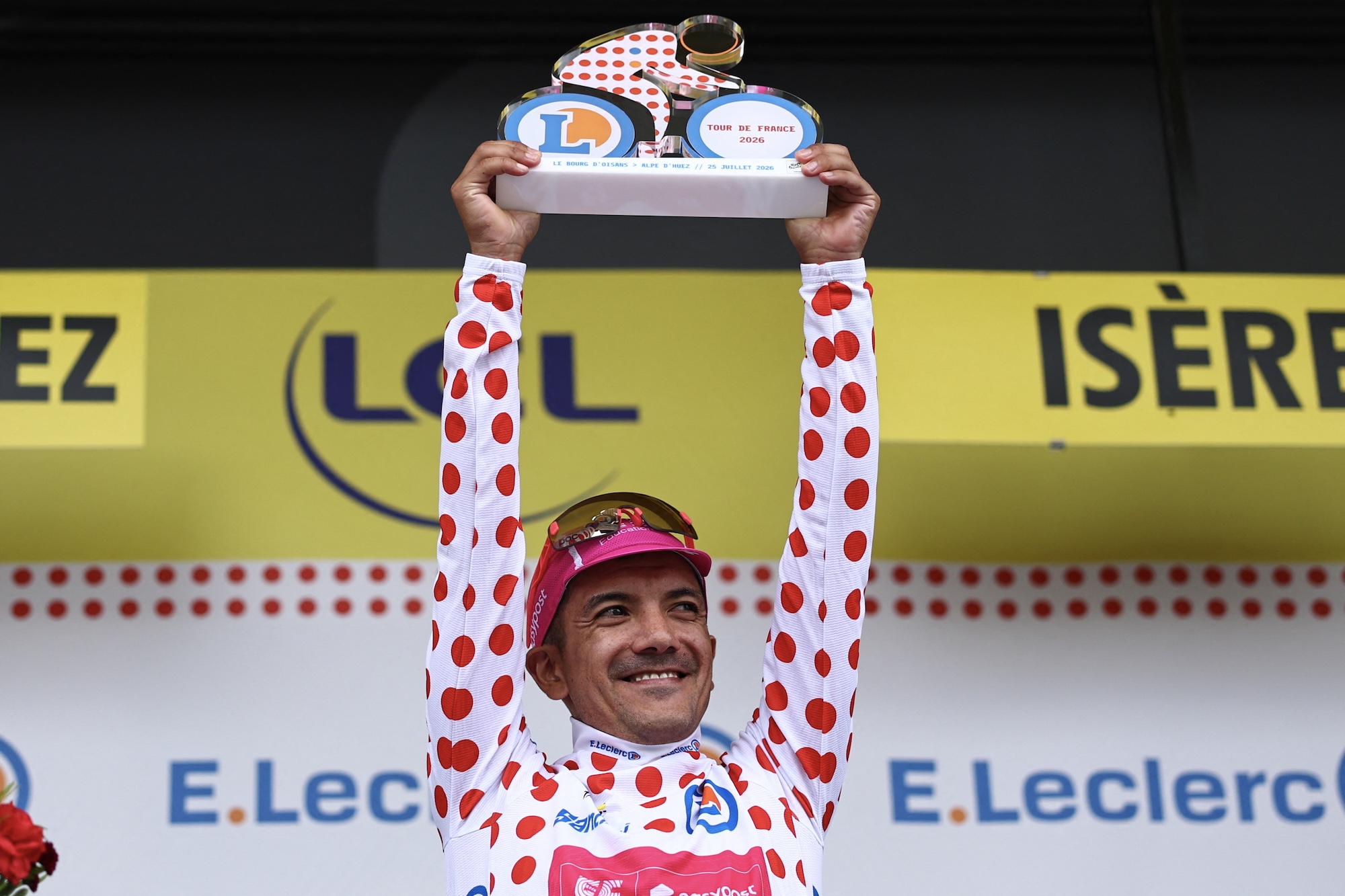 Richard Carapaz hoists the best climber's trophy after stage 20 and will wear the polka dot jersey on the final day into Paris