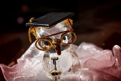 A glass figurine of an owl wearing a graduation cap. 