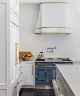 blue range cooker in a white kitchen with brass hardware