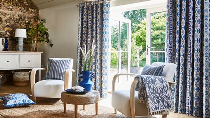 Small living room Feng Shui mistakes are worth avoiding. Here is a bright living room with blue curtains, white chairs with blue pillows, and open French doors into the sunny garden