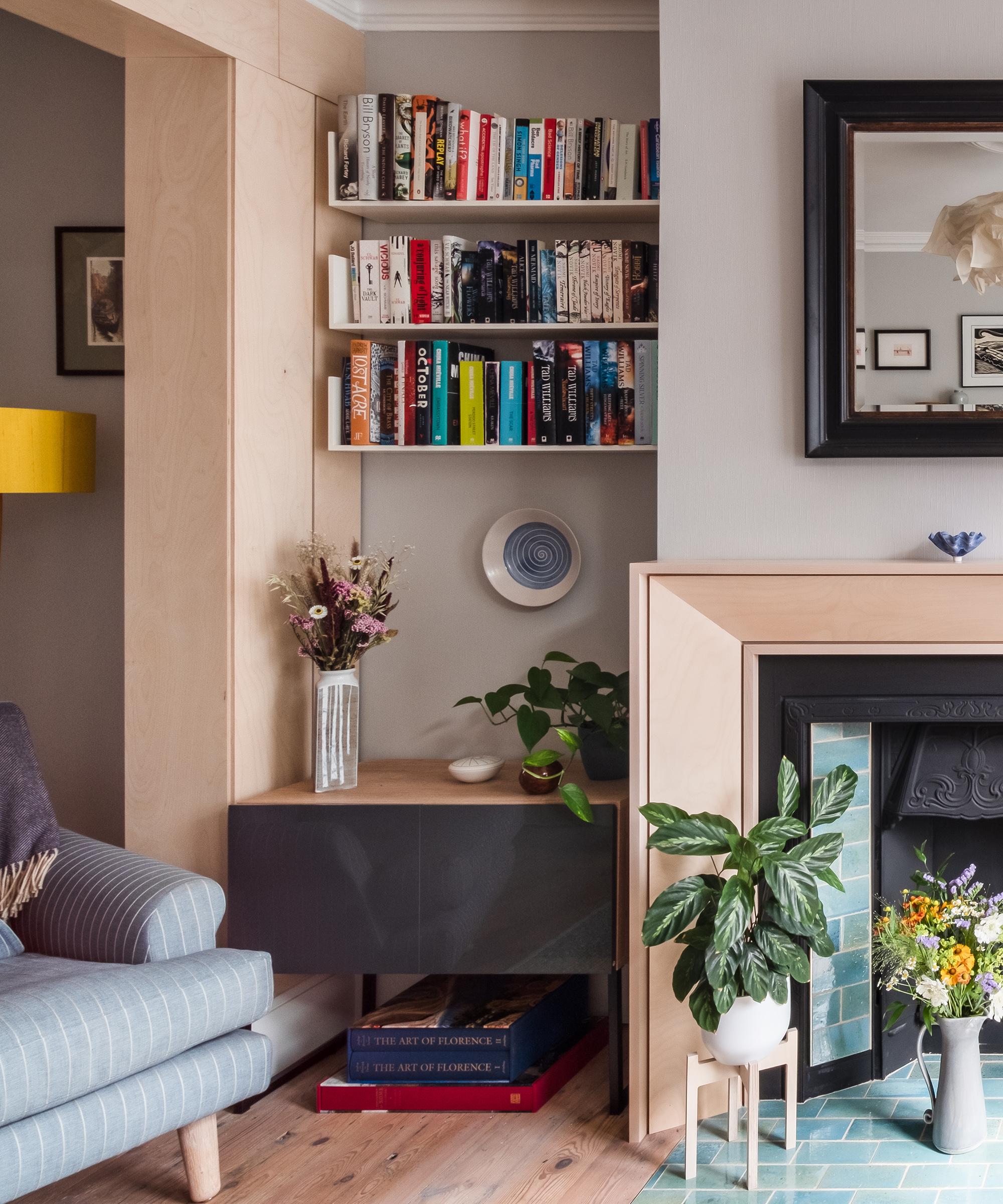 Bookshelves in an alcove aside a fireplace in a contemporary living room in a Victorian house