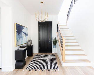 White entryway with contemporary art, black door and sriped rug