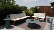 An outdoor patio area with pavers, white furniture, and a wooden fence