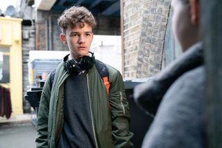 Ricky Mitchell looks stunned with headphones around his neck in EastEnders 