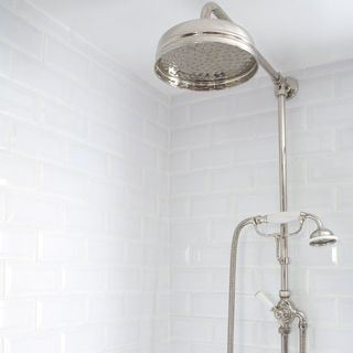 bathroom with shower on white tiled walls