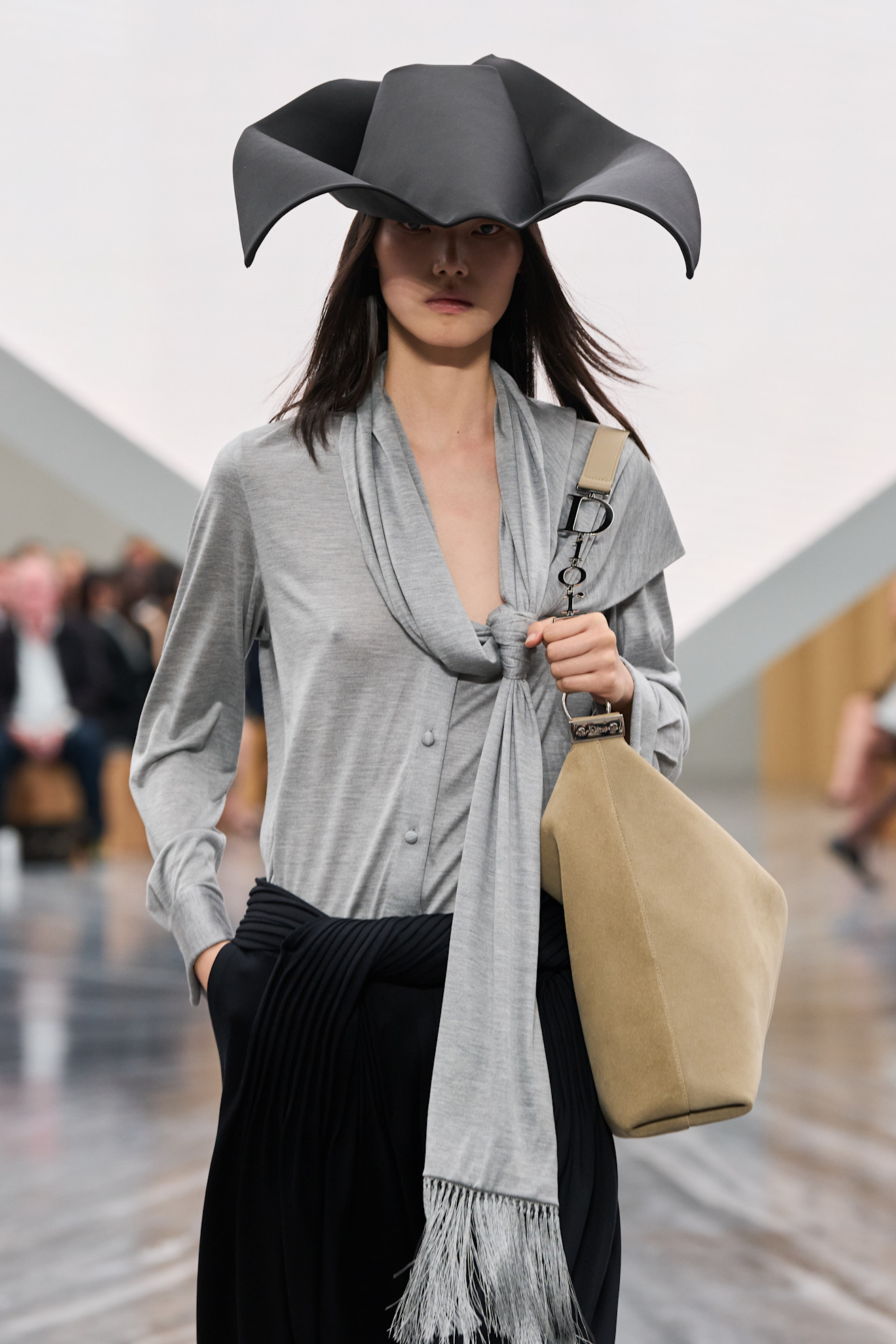 a model carries the dior diorly bag on the runway.