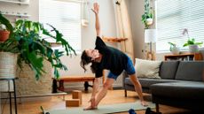 Woman performing Trikonasana yoga pose in a domestic setting